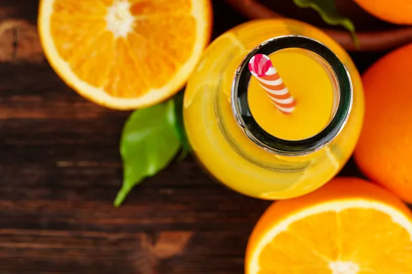 Bottle of orange juice with oranges on wooden table — Stock Photo, Image