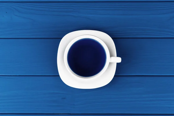 전형적 인 파란색 배경에 놓인 접시 위에 놓인 커피 한 잔의 맨 위 사진 — 스톡 사진