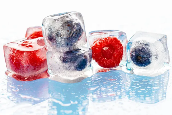 Frozen berries in ice cubes on pink — Stock Photo, Image
