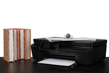 Yazıcı ile çalışma masası ve beyaz çekmeceler üzerine istiflenmiş kitaplar