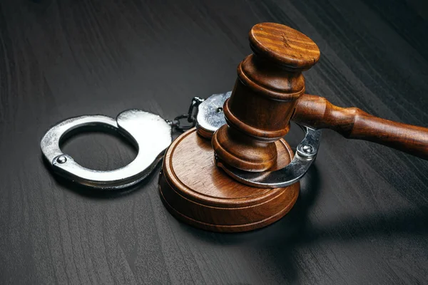 Суддя дав їй наручники на дерев'яному столі — стокове фото