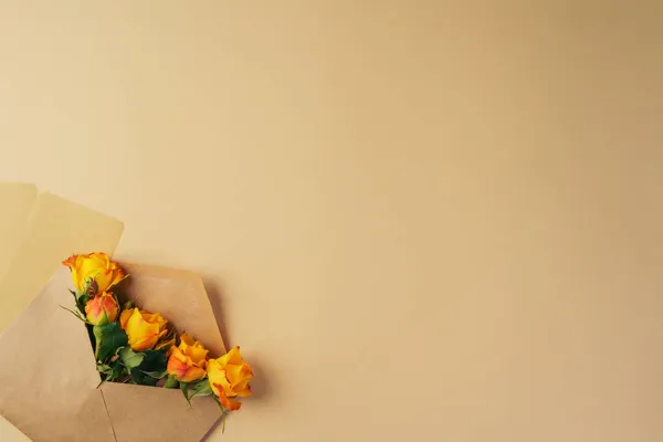 Паперовий конверт з жовтими трояндами на бежевому фоні — стокове фото