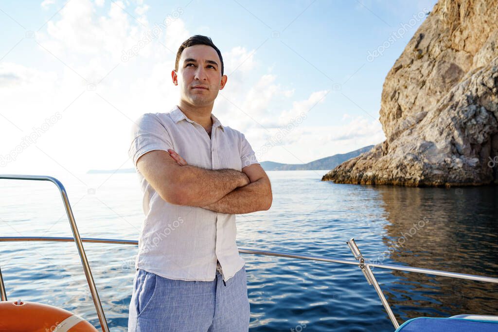 Young man in white shirt standing on the nose yacht in the sea