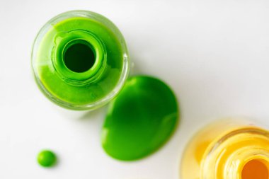 Beyaz arka planda damlayan parlak renkli tırnak cilası şişeleri