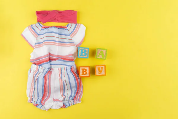 赤ちゃんの女の子の服の上からの眺め黄色の背景 — ストック写真