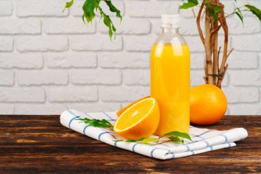 Ahşap masanın üzerinde beyaz tuğla duvar zeminine karşı bir şişe taze portakal suyu.