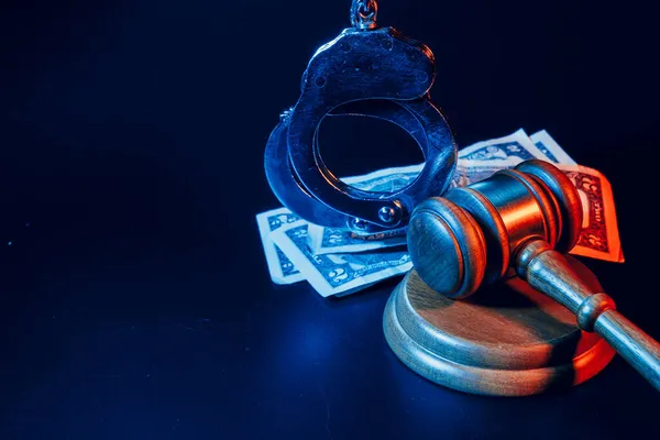 Bribe concept. Dollar banknotes, handcuffs and gavel on dark black table — Stock Photo, Image