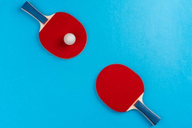 Mavi arka planda pinpon raketi ve top.