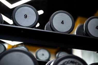 Spor salonunun rafındaki yeni halterleri kapatın.