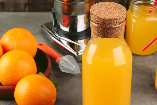 En flaske appelsinjuice med appelsiner på trebord – stockfoto