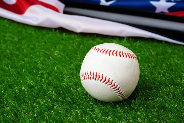 Μπέιζμπολ ρόπαλο και μπάλα με αμερικανική σημαία στο γρασίδι — Φωτογραφία Αρχείου