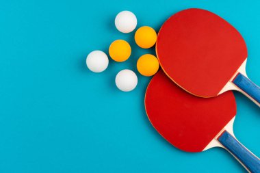 Mavi arka planda pinpon raketi ve top.