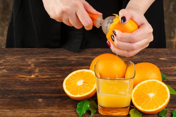 Woman hand squeezes orange juice close up — Stock Photo, Image