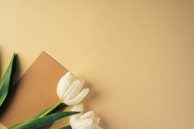 Bej arka planda yeni lalelerle çevrili kağıt kart.