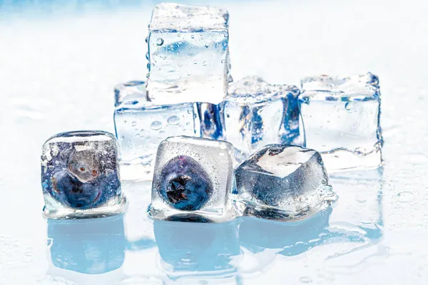 Las bayas congeladas en los cubos de hielo sobre rosado —  Fotos de Stock