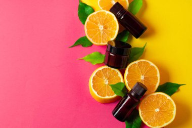 Turunçgil yağı. Pembe arka planda dilimlenmiş narenciye ve aroma şişeleri.
