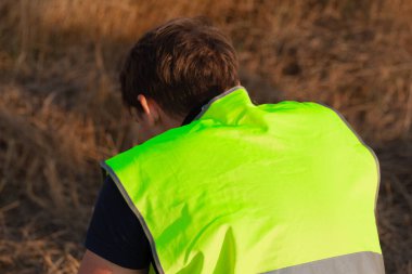 Sarı yelekli adam havaalanında uçak gözlemi yapıyor.