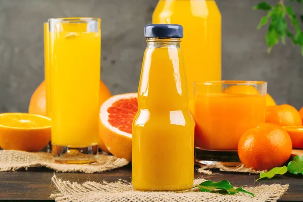 Botella de jugo de naranja con naranjas sobre mesa de madera — Foto de Stock