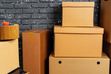 Kara tuğla duvara karşı boş odada yığınla karton kutu.