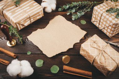 Noel eşyalarıyla süslenmiş, eski ahşap arka planda tüy olan boş bir mektup.
