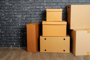 Kara tuğla duvara karşı boş odada yığınla karton kutu.