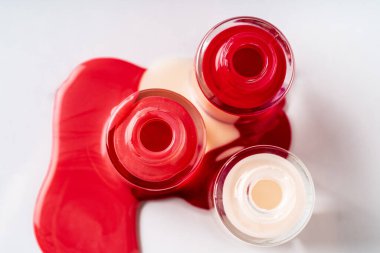 Beyaz arka planda birkaç şişe tırnak cilası açılmış.