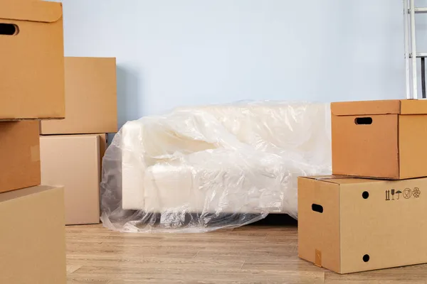 Упаковані побутові речі в коробки і упакований диван для переміщення — стокове фото