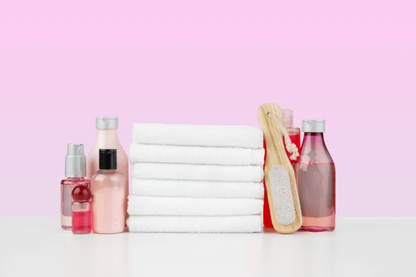 Pila di asciugamani bianchi e bottiglie di skincare sul tavolo bianco — Foto Stock