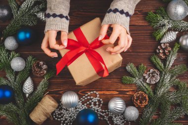 Noel süslemeleri ahşap masada, süslü hediyeler de kadınların elinde.