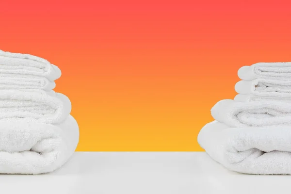 Toallas limpias apiladas sobre mesa blanca contra fondo de color —  Fotos de Stock