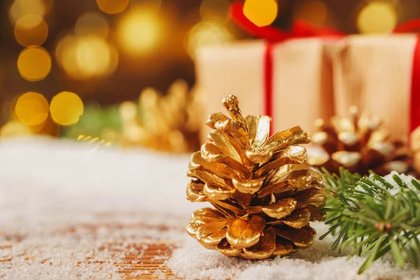 Gouden beschilderde dennenappel op besneeuwde tafel, kerstdecor — Stockfoto