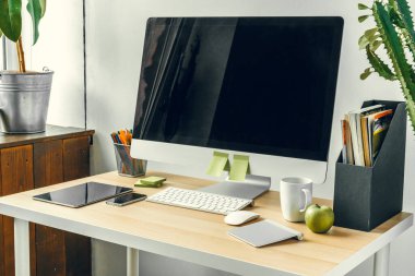 Ofis ya da ev işi. Ofis masasında malzemelerle siyah ekranlı bilgisayar monitörü