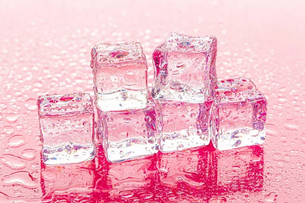 Fozen ijsblokjes op natte roze achtergrond — Stockfoto