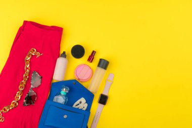 Parlak sarı arka planda aksesuarları olan şık bir kadın kıyafeti.