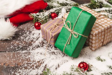 Tahta arka planda köknar ağacı dalları ve karla kaplanmış kırmızı mücevherlerle sunuluyor