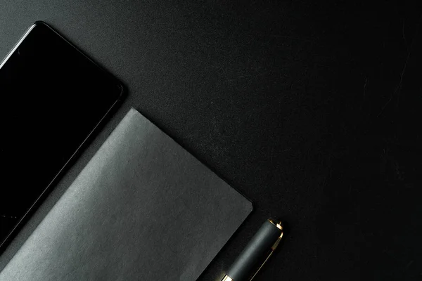 Blocco note nero con penna su tavolo nero da vicino — Foto Stock