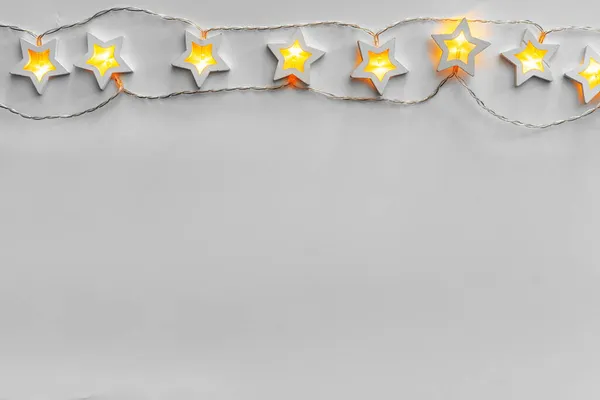 Illuminated star shaped garland on light gray background — Stock Photo, Image