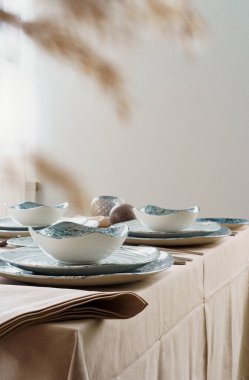 Bej masa örtüsü üzerinde şık bulaşık takımı olan masa ayarları