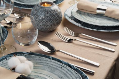 Bej masa örtüsü üzerinde şık bulaşık takımı olan masa ayarları