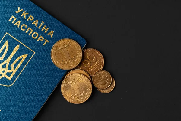 Український паспорт з україніанськими гривінськими монетами. Убогість і імміграція — стокове фото