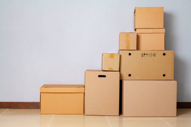 Gri duvara karşı yerde hareket etmek için karton kutular
