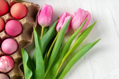 Yumurta kutusuna boyanmış Paskalya yumurtaları ve taze laleler.