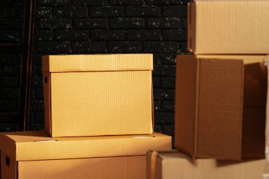 Kara tuğla duvara karşı boş odada yığınla karton kutu.