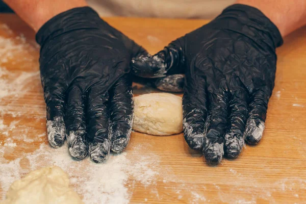Szef kuchni w czarnych rękawiczkach przygotowuje ciasto z bliska — Zdjęcie stockowe