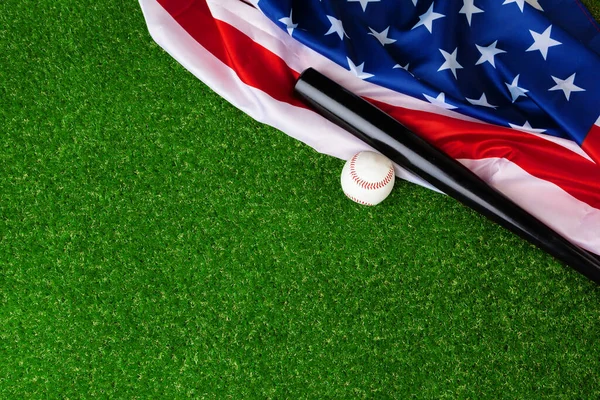Baseball bat i piłka z amerykańską flagą na trawie — Zdjęcie stockowe