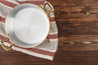 Tahta masa örtüsü olan bakır tencere.