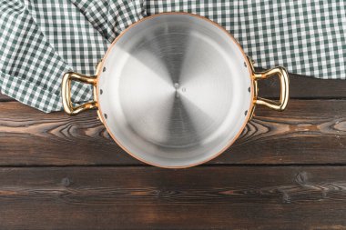 Tahta masa örtüsü olan bakır tencere.