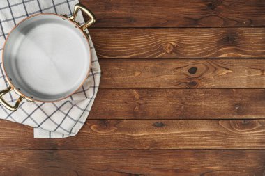 Yeni bakır tencere ahşap masada, yukarıdan görünüyor.