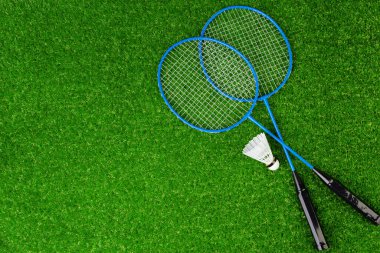 Badminton oyun raketleri ve çimlerin üzerinde mekikçik.