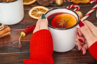 Bir bardak sıcak şarap, kadınların ellerinde, ahşap masanın üstünde.
